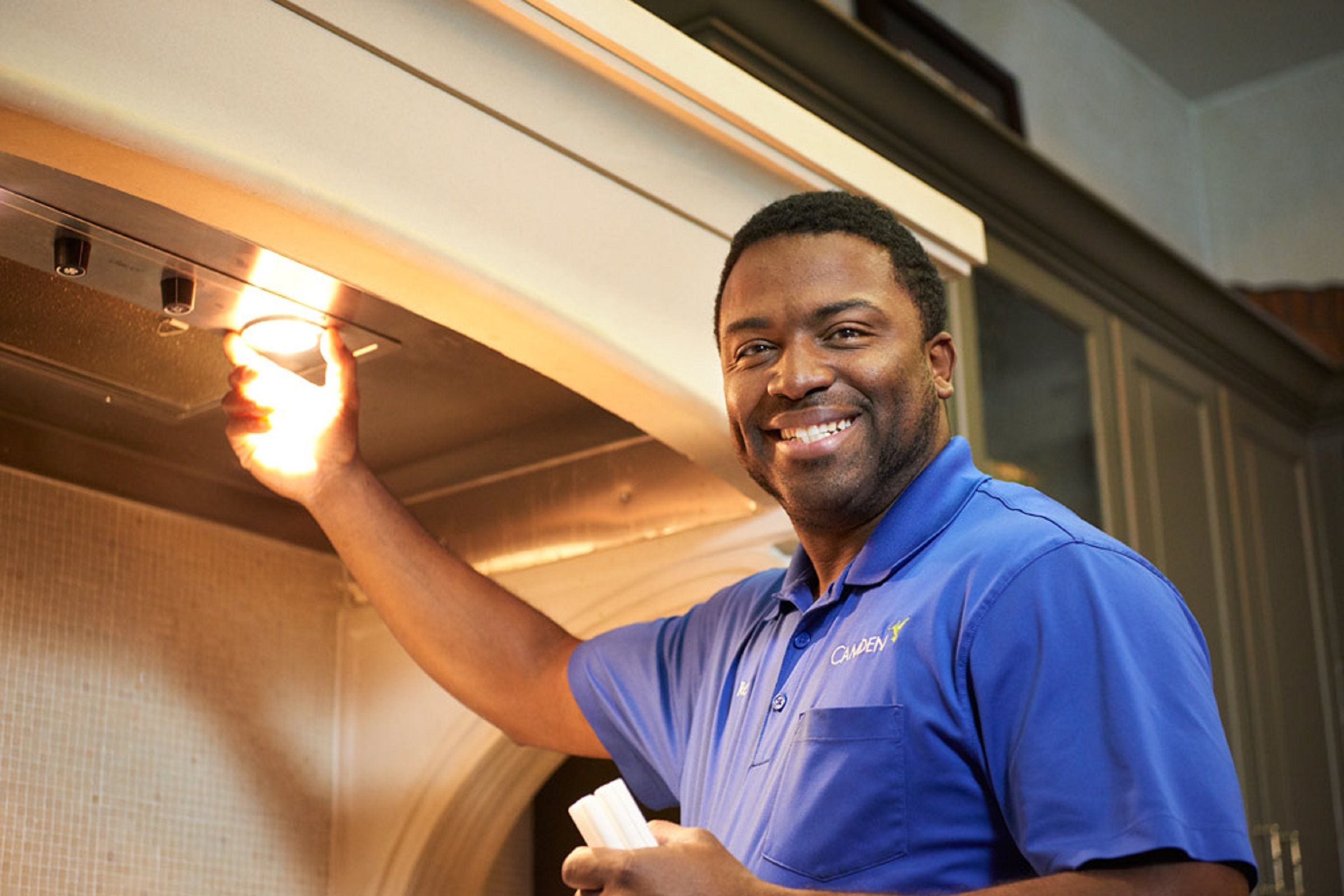 Camden associate smiling while changing a light under a kitchen range hood